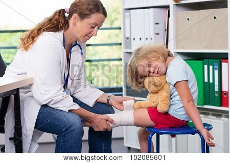 Female Doctor Bandaging The Leg From A Of Girl