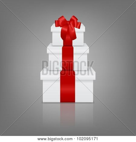 Stack of three realistic white gift boxes with red ribbon and bow
