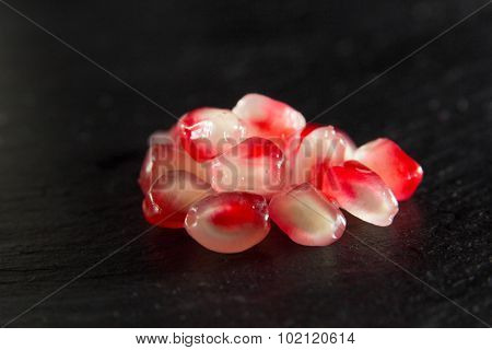 Small Heap Of Pomegranate Seeds On Black Slate Surface