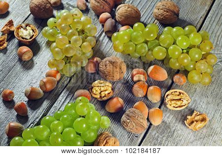 Grapeberries, Hazelnuts And Walnuts On A Wooden Table