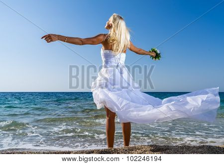 Young bride in white wedding dress  on the beach in Greece