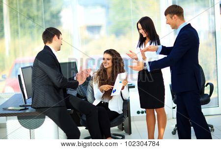 Young businesspeople clapping for female colleague after presentation