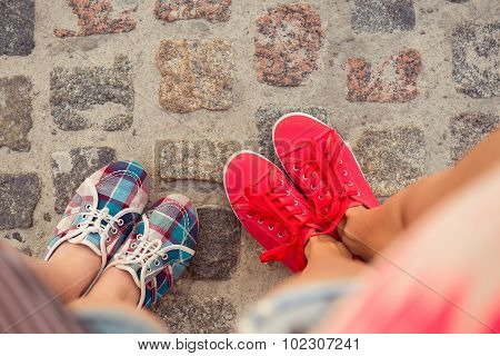 Top View Of A Two Pairs Of Sneakers Shoes Walking On Paving Ston