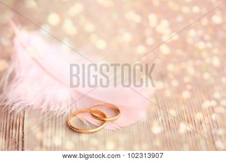 Wedding  Background with Gold Rings, pink feather and golden magical lights 