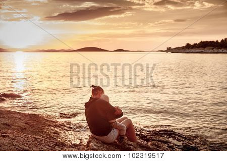 Mother With Children Sitting On Beach, Watching Sunset