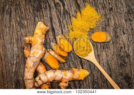 Turmeric Powder In Spoon And Roots On Wooden Plate