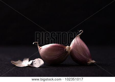 A Still Life Arrangement Of Three Whole Garlic Bulbs Grouped On Black Stone Plate
