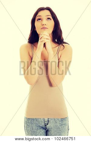Young woman praying with her hands together and looking up.