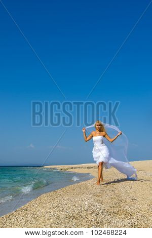 Young bride in wedding drees having fun on the beach in Greece