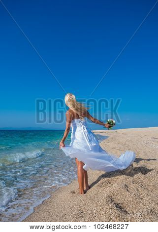 Young bride in wedding drees having fun on the beach in Greece