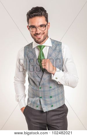 Picture of a young business man wearing a white shirt, grey vest and green tie.