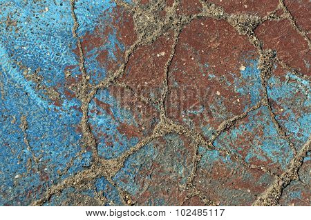 Blue And Brown Paint On Damaged Asphalt.