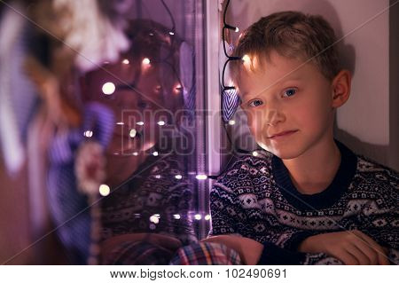 Calm Little Boy On The Windoe With Christmas Lights