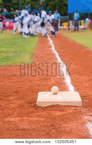 Baseball And Base On Baseball Field With Players And Judges On Background