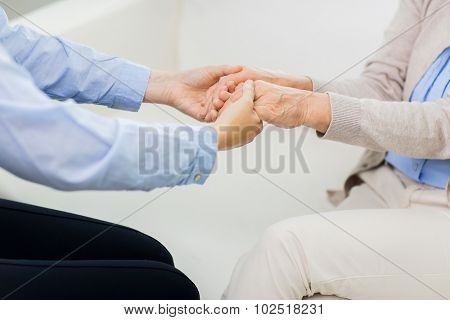 people, age, family, care and support concept - close up of senior and young woman  holding hands