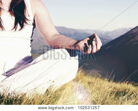 Lady meditating in lotus position on top of the mountain Concept