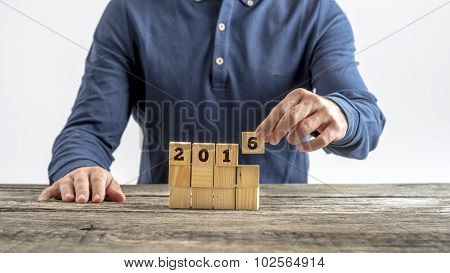 Front View Of A Man Assembling A 2016 Sign With Wooden Cubes