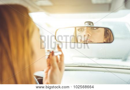 Woman Putting Lipstick In The Car. She Watch Herself In The Mirror While She Is Driving