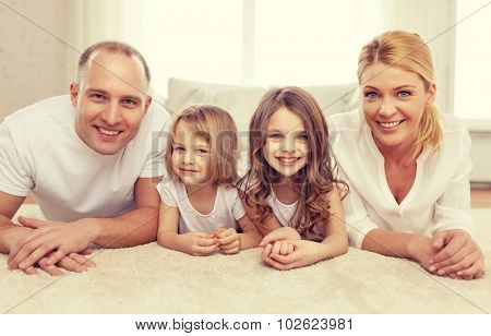 family, children and home concept - smiling family with and two little girls lying on floor at home