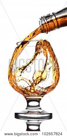Whisky poured to glass from buttle with splashes on white