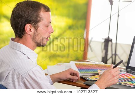 Man working on laptop while holding up palette, colormap from behind angle