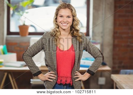 Portrait of confident businesswoman with hands on hip standing in bright office