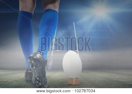 Low section of rugby player about to kick the ball against rugby pitch