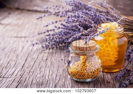 Arrangement of small glass jars with lavender honey, honeycombs and bee pollen