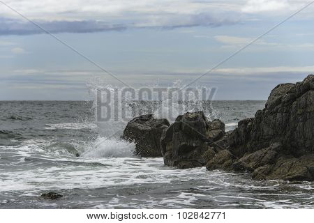 Waves breaking on the rocks .