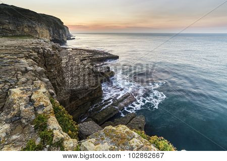 Stunning Coastal Landscape With Long Exposure Waves Crashing At Sunrise