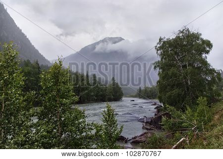 River In Valley Between The Mountains On Mist Fog  Rainy Weather