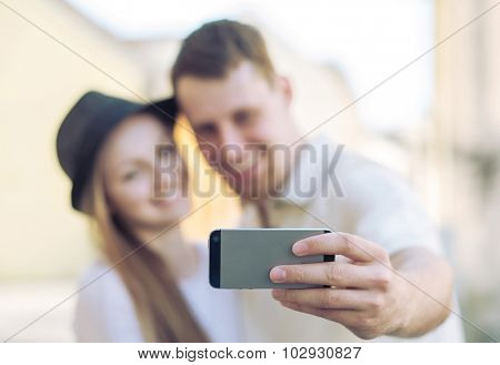 Touristic couple shooting on the modile phone at the city streets under sunlight.