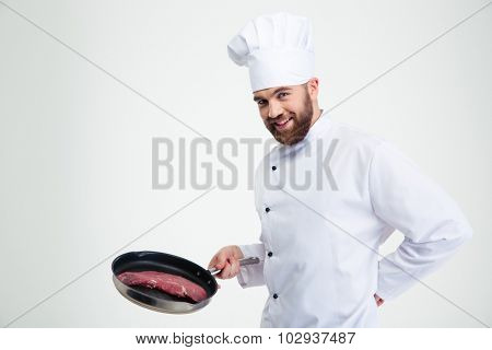 Portrait of a cheerful chef cook holding fresh meat on pan isolated on a white background