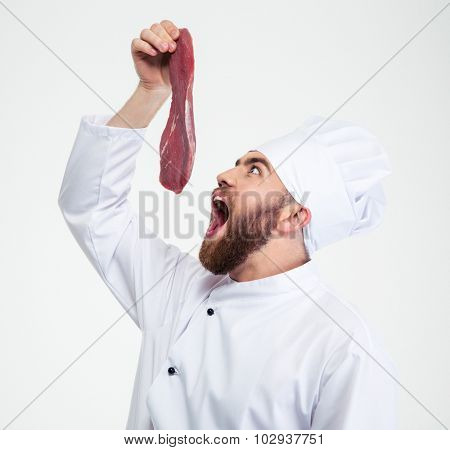Portrait of a funny chef cook reading to eat fresh meat isolated on a whtie background