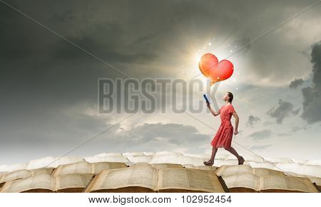 Young woman in red dress running with book in hand