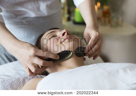 Young woman have face guasha treatment at asian beauty clinic