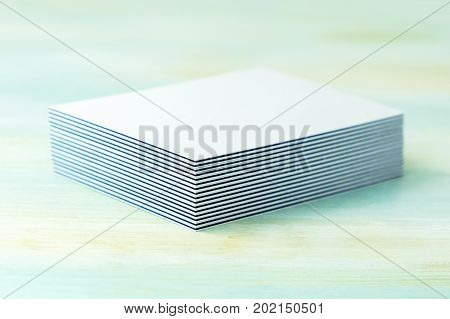 A stack of blank layered business cards with painted edges, on a teal background, with a shallow depth of field. Selective focus photo, place for text.