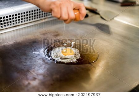 Hand Of Chef Cooking Egg On Hot Pan In Front Of Customers.