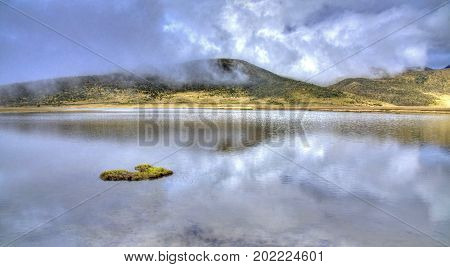 Lake Limpiopungo, in the Cotopaxi National Park, on a foggy and cloudy morning, reflecting the sky and mountains. Ecuador.