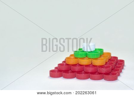 Regular Quadrangular Pyramid Of Whites, Reds, Greens, Oranges Striped Caps Of Plastic Bottles
