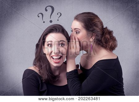 A teenager girl looking confused with drawn question marks above the head, while a girlfriend whispers something in her ear concept.