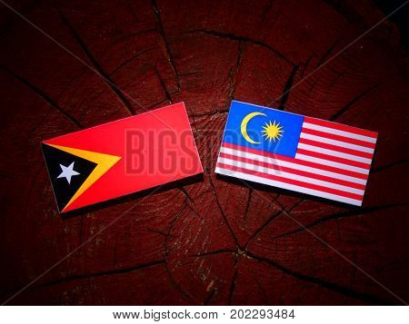 East Timorese Flag With Malaysian Flag On A Tree Stump Isolated