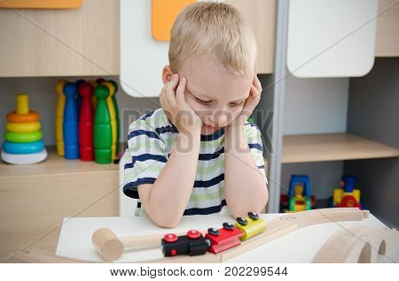 Bored Sad Little Boy Sitting At Table