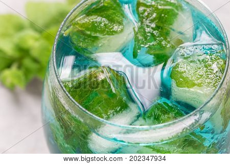 Trendy blue moscato wine in a glass served with mint ice cubes horizontal closeup