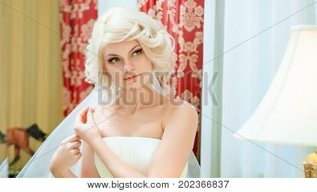 The blonde bride admires her veil in the mirror. Morning of the bride.