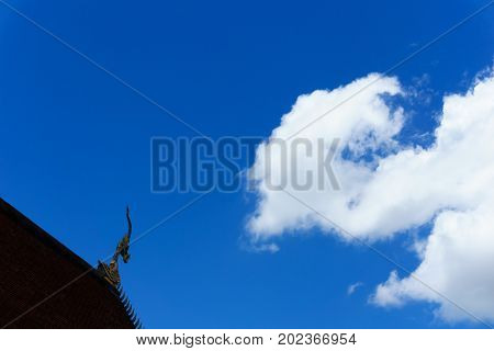 Statue Of The Head Of The Serpent On The Top Of Roof With Blue Sky And Cloud Shape Like Serpent.
