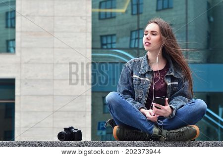 A Girl Photographer Uses A Smartphone And Sits On A Granite Parapet