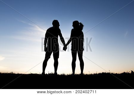 A silhouette of romantic lovers with sunset on the back