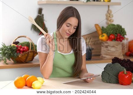 Young  woman is making online shopping by tablet computer and credit card. Housewife found new recipe for  cooking in a kitchen.