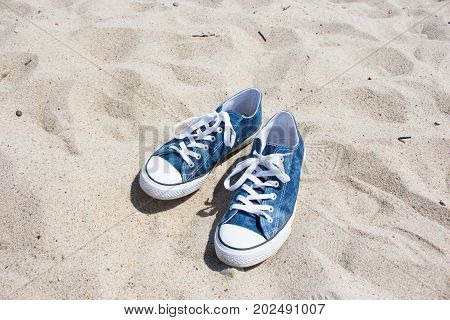 blue shoes with white laces lying on the sand